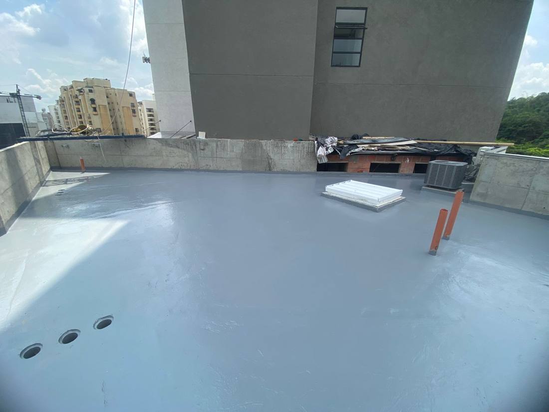 Terraza impermeabilizada con acabado gris uniforme y la ciudad al fondo