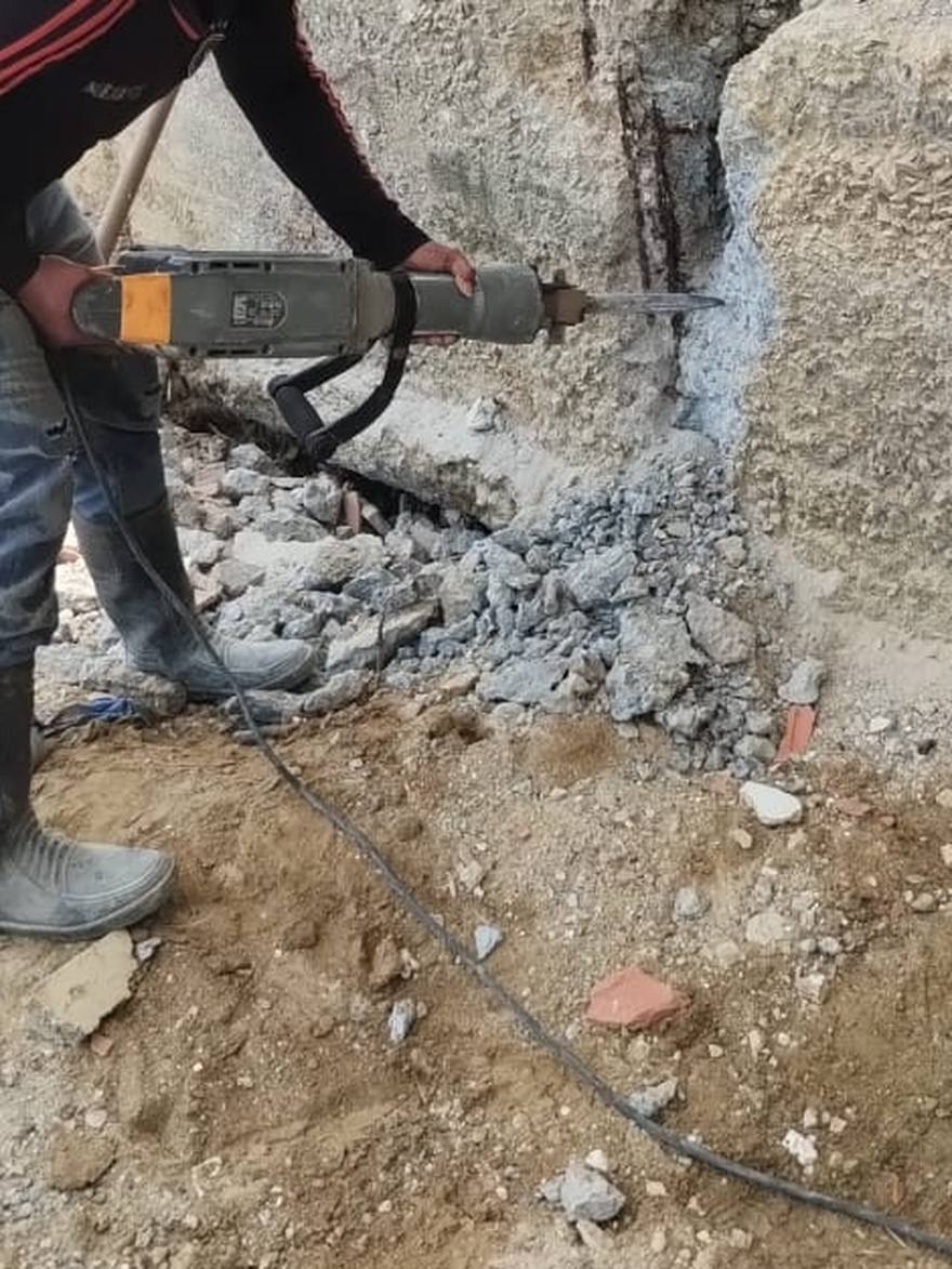 Demolición de una viga de concreto con martillo neumático, con el escombro en primer plano